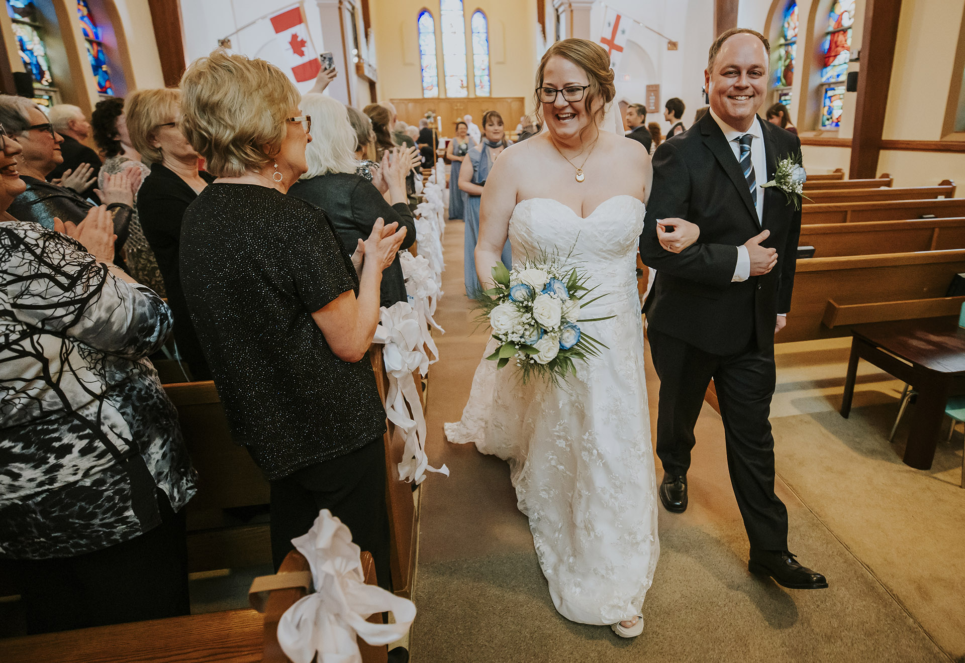 Bride and groom smiling walking down the aisle in a church in downtown Sudbury