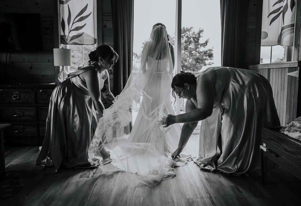 Bridesmaids helping the bride with her dress during an intimate wedding in Sudbury, Ontario captured by a Sudbury Ontario wedding photographer