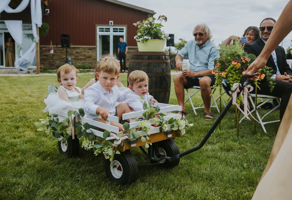 kids entering the ceremony in a little car during a wedding in Sudbury, Ontario captured by a Sudbury Ontario wedding photographer