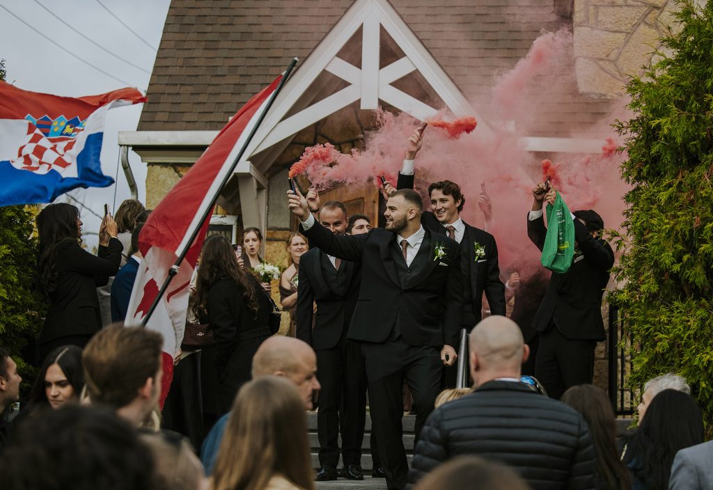 Wedding party leaving the ceremony with Croatian and Canadian flags with red smoke flares in Sudury, Ontario