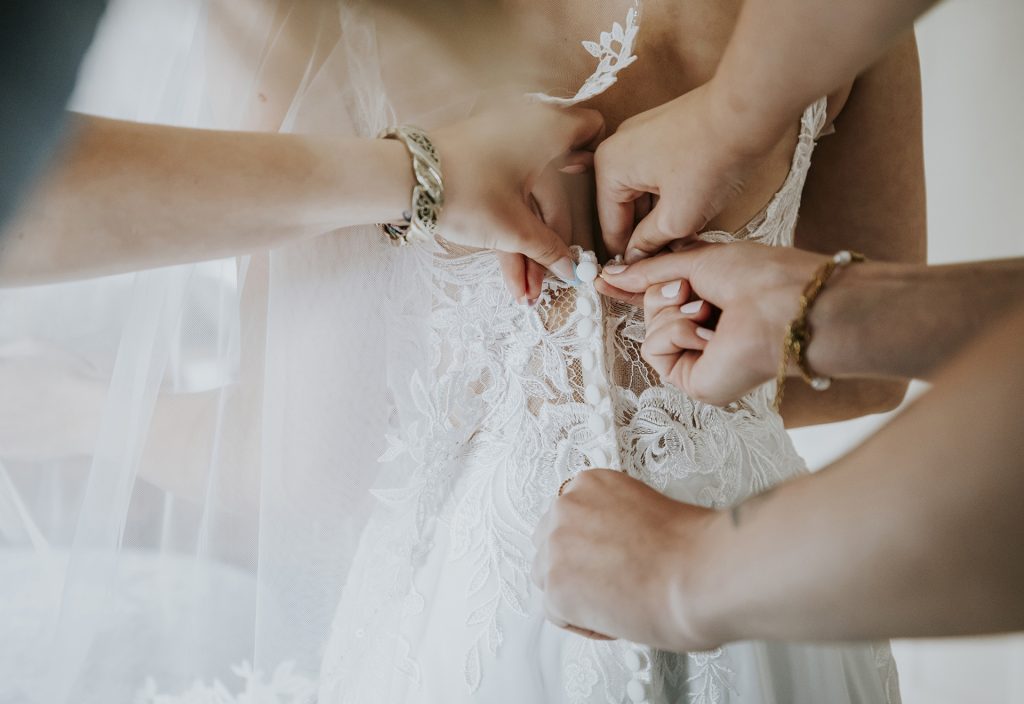 Details of hands helping the bride with her wedding dress in Sudbury, Ontario